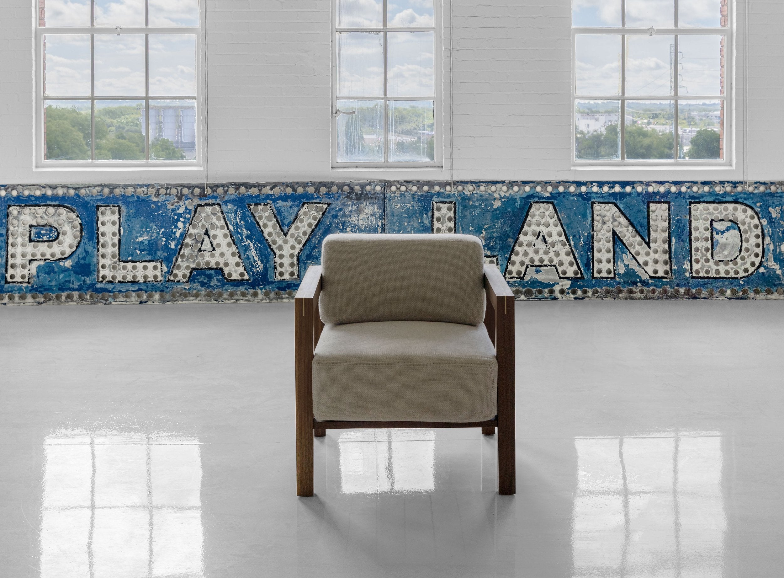 Chair in a room with large windows and a decorative wall sign reading 'PLAYLAND'.