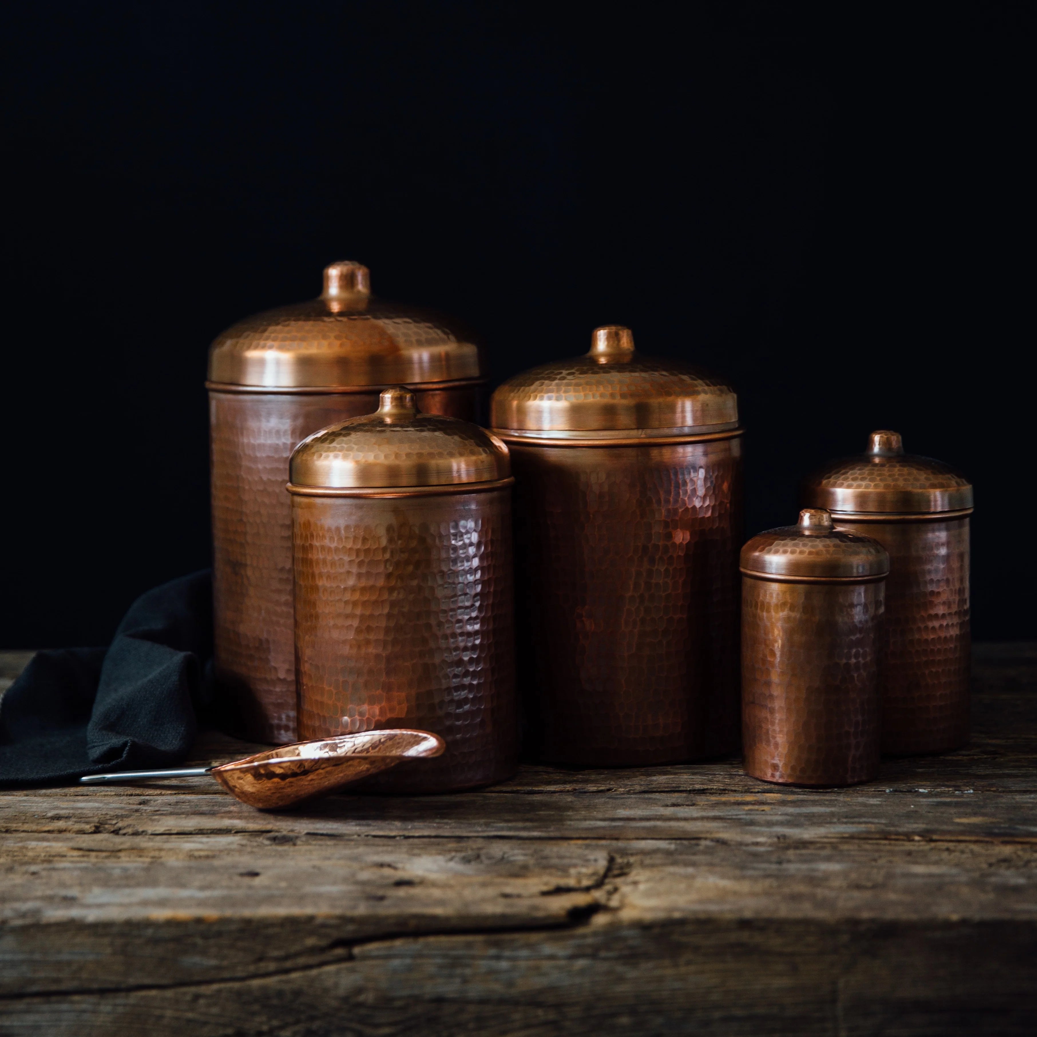 Set of copper canisters on a wooden surface with a dark background