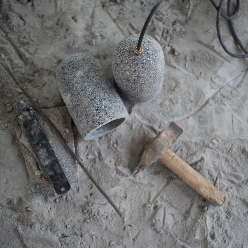 Two concrete cups on a textured surface with a hammer and trowel.