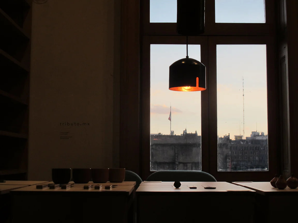 Dining area with a large window view of a cityscape during sunset.