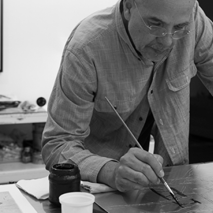 Man writing at a desk with a blackboard in the background