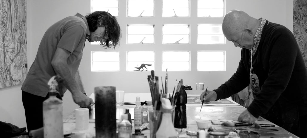 Artists creating artwork inside a sunlit creative workshop in black and white.