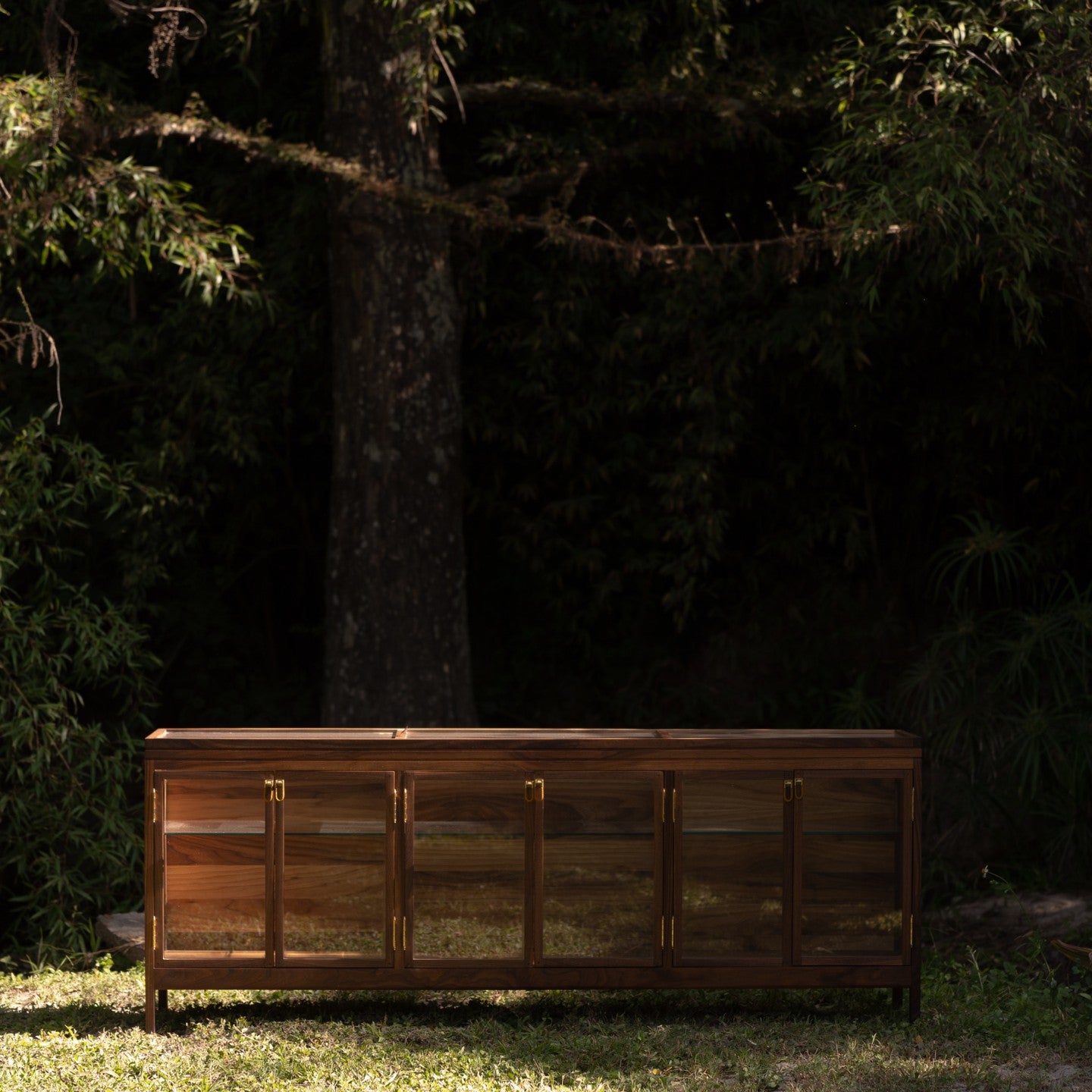 Wooden sideboard with gold handles in a forest setting